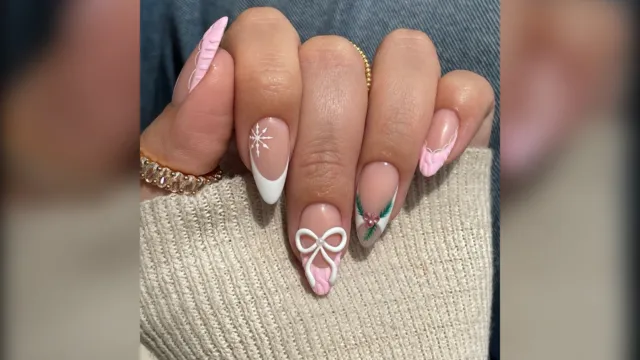 Almond nails with pink French tips, a white bow and holly, almond Christmas nails
