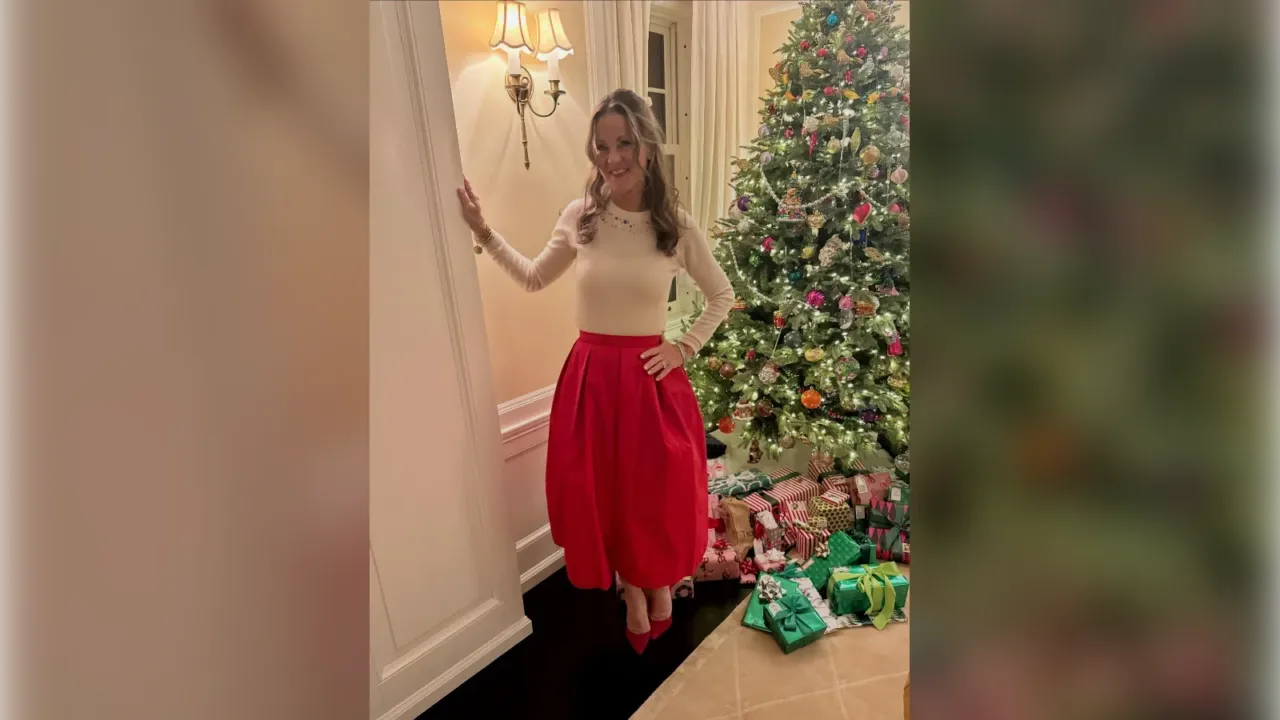 Woman in a cream top and full red taffeta skirt next to a Christmas tree, Christmas Eve outfit