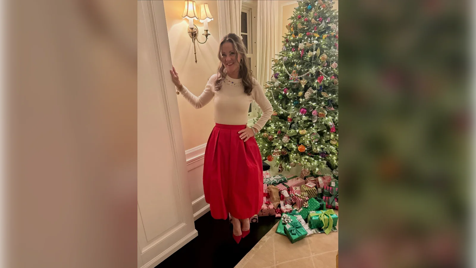 Woman in a cream top and full red taffeta skirt next to a Christmas tree, Christmas Eve outfit