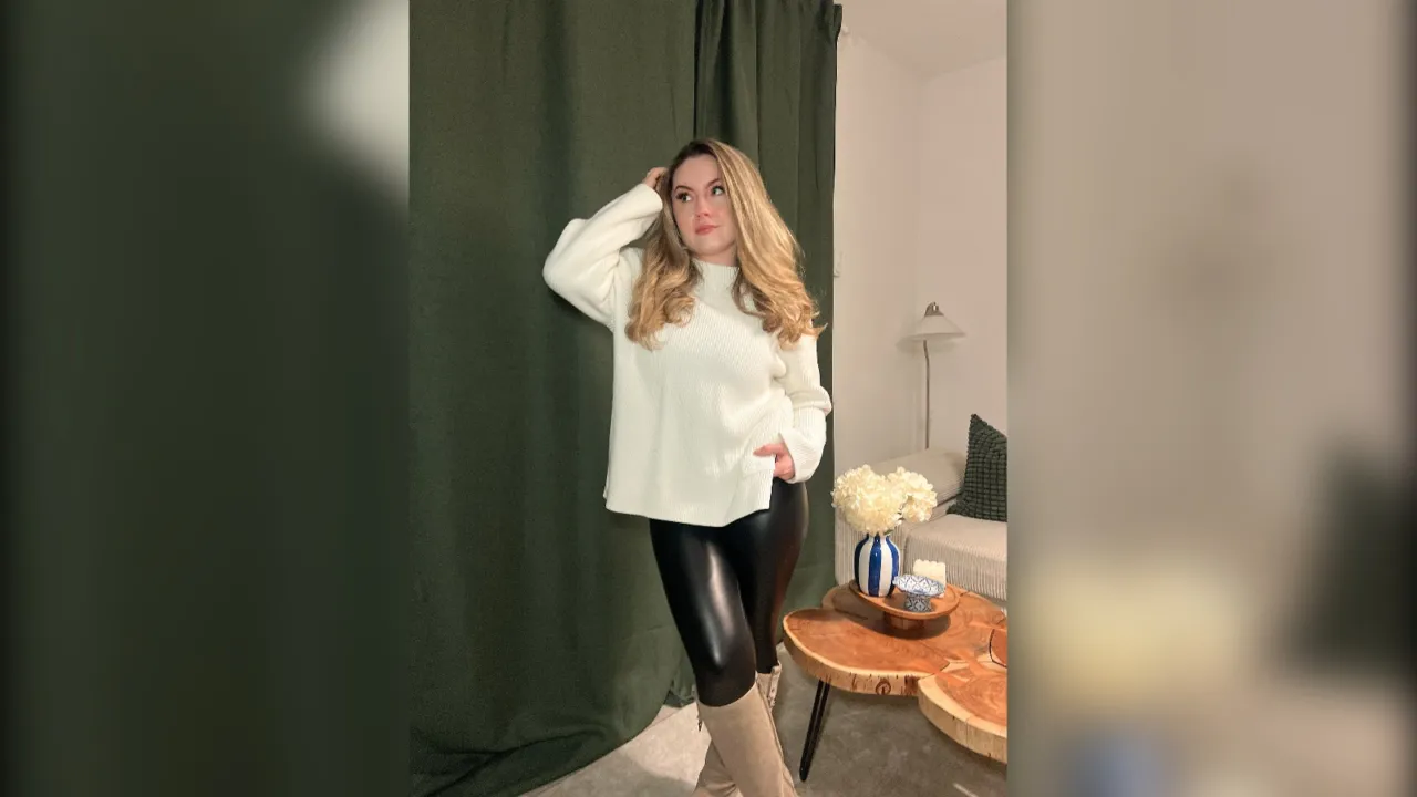 Woman in a cream chunky sweater and black faux leather leggings