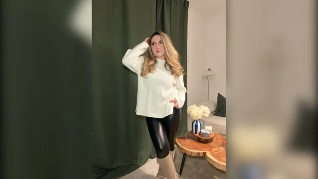 Woman in a cream chunky sweater and black faux leather leggings