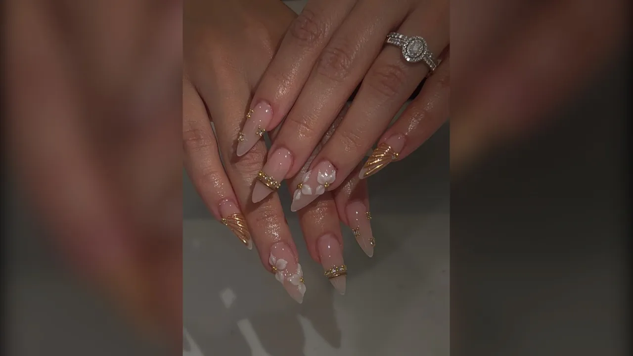 Long almond nude nails with gold chrome French tips and white snowflakes
