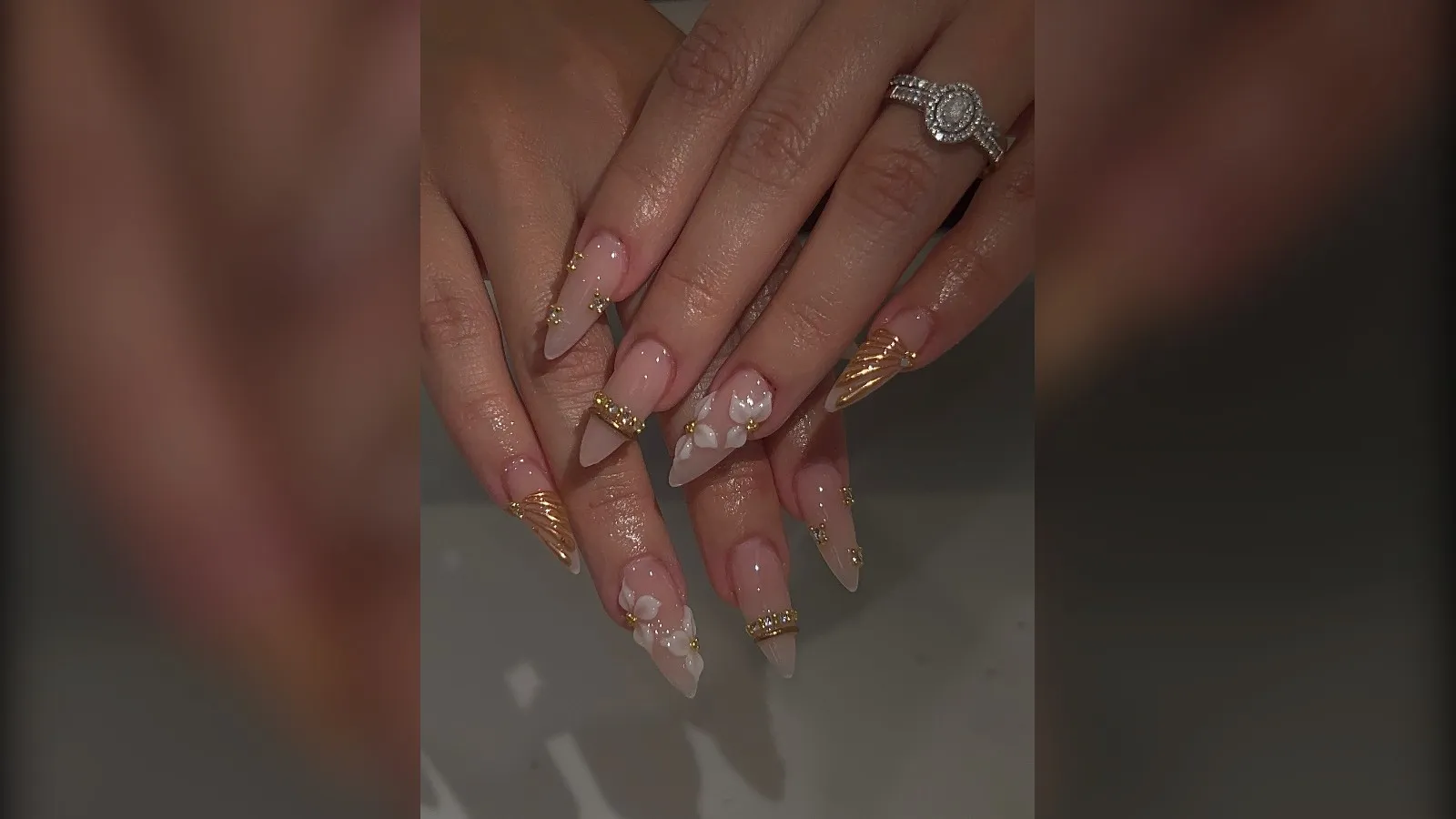 Long almond nude nails with gold chrome French tips and white snowflakes