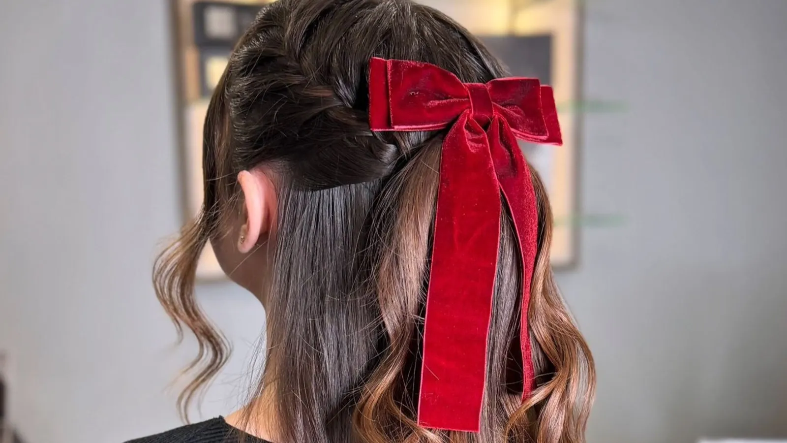 Half up curly hairstyle with a big red velvet bow