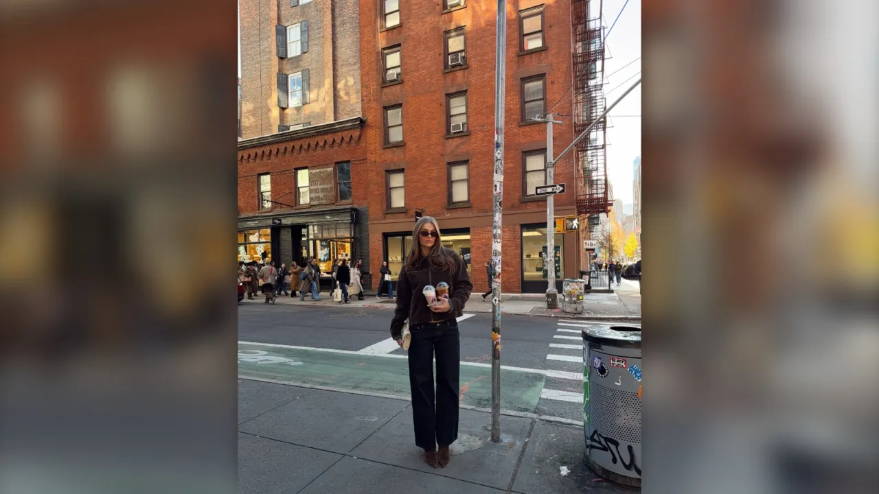 Woman in a dark winter coat and black pants standing on a New York City street