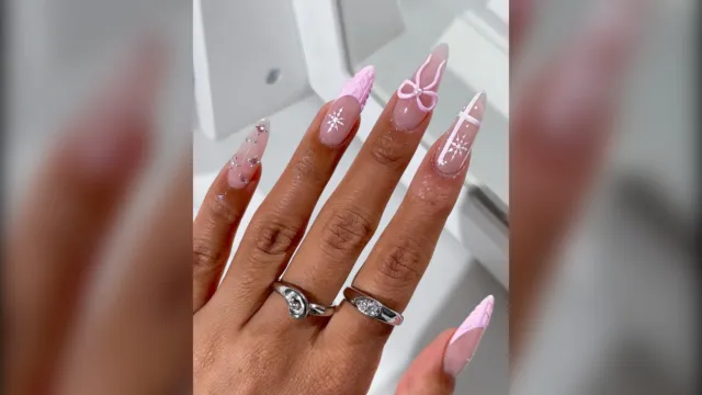 Long almond pink nails with a 3D pink bow and white snowflakes