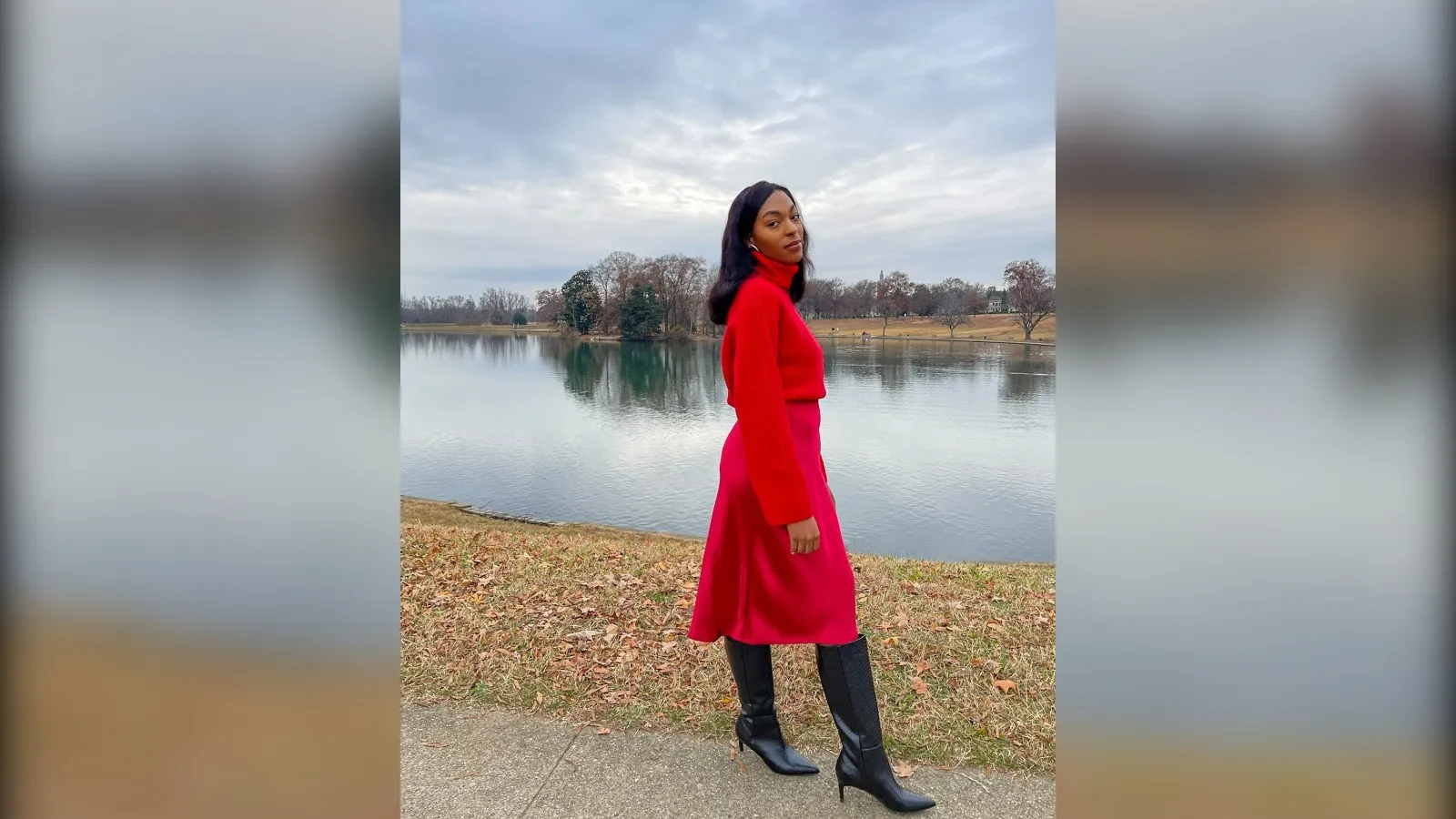 Woman in a red turtleneck and red satin skirt by a lake