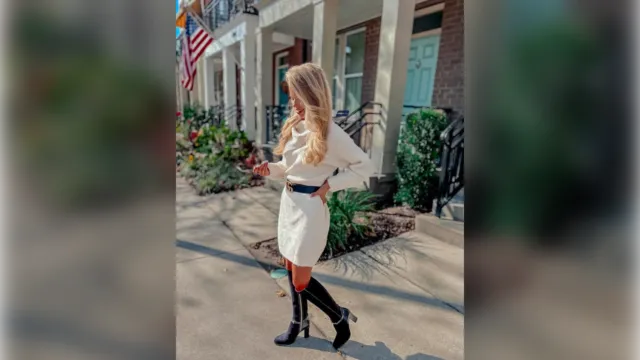 White cable knit sweater dress with a black belt and black knee boots
