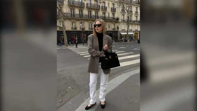 Woman in a black turtleneck, brown blazer and white jeans in the city