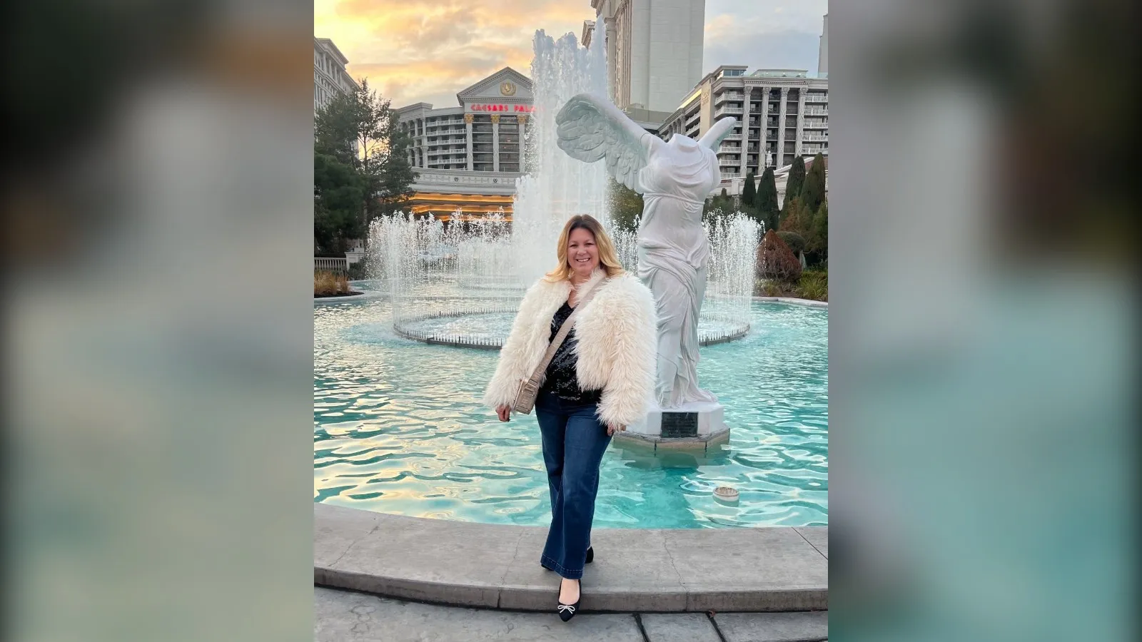 Woman in a white faux fur jacket and flare jeans by the Caesars Palace fountain, Vegas winter outfit