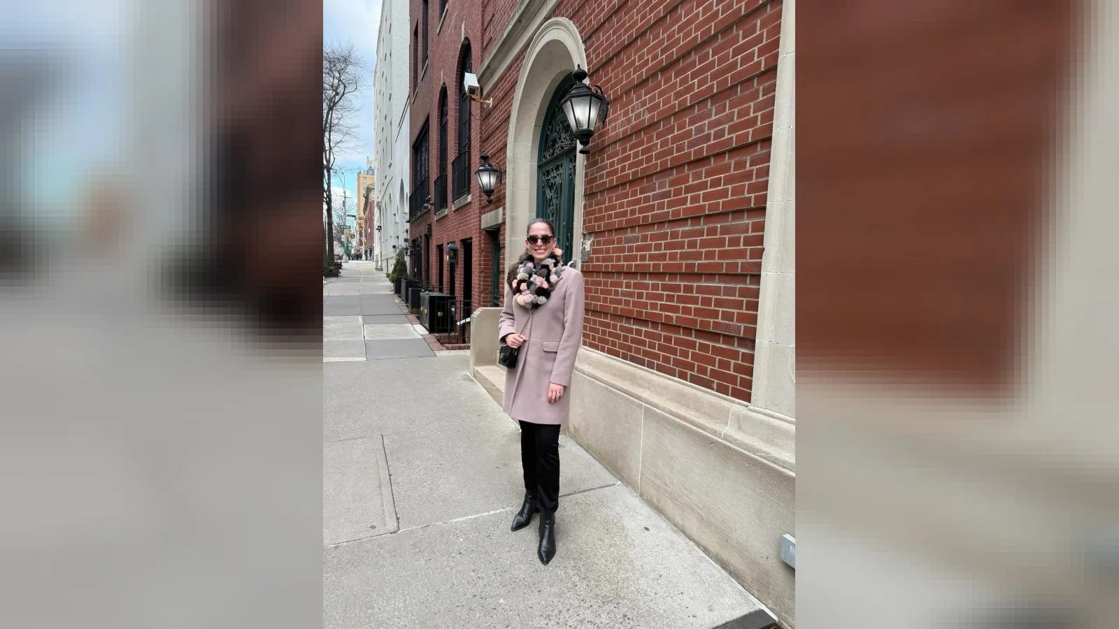 Woman in a pink winter coat, black flare jeans and black ankle boots on a sunny winter day in New York City