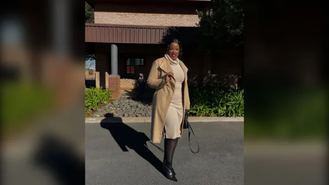 Woman in a camel coat, cream knit dress and black tights, winter church outfit