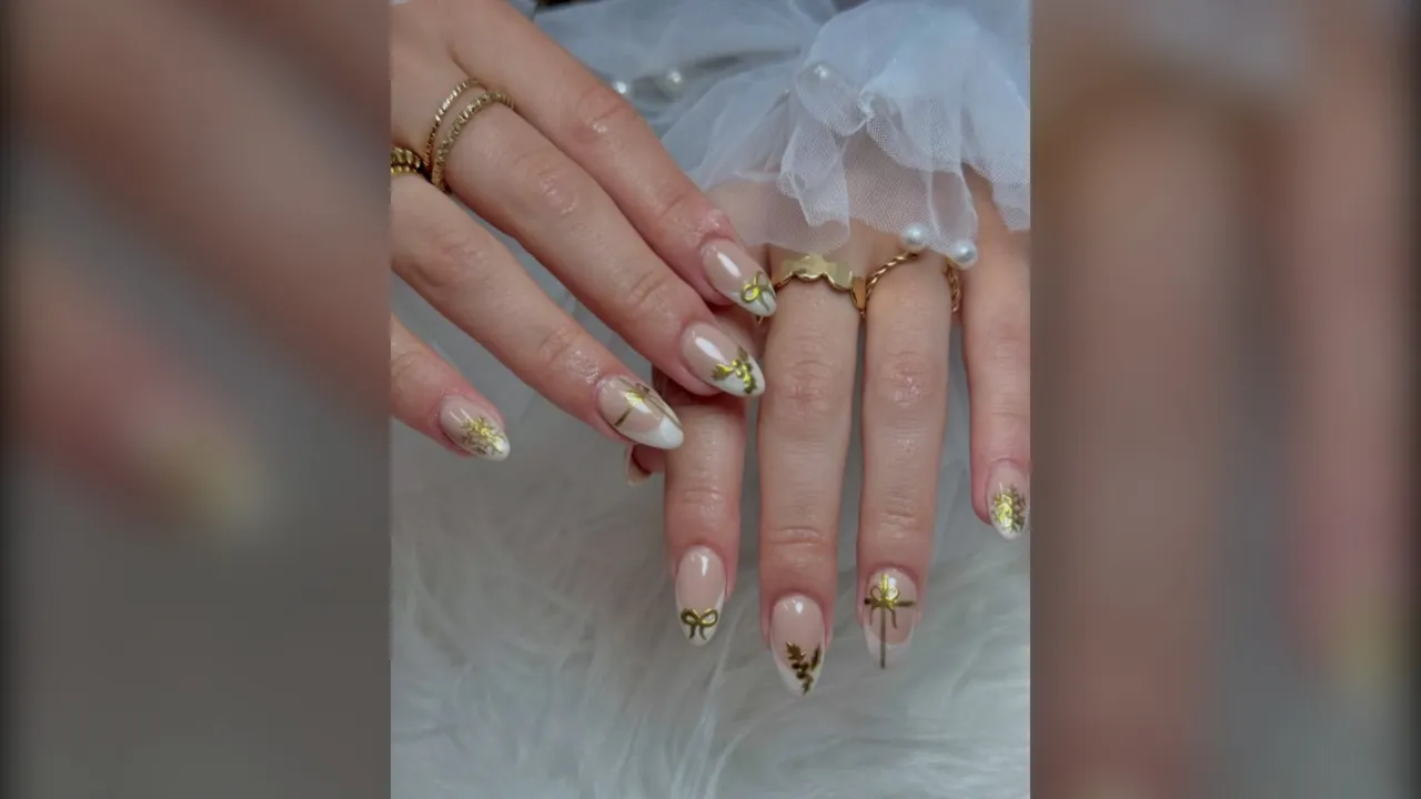 White chrome French tip almond nails with small gold bows