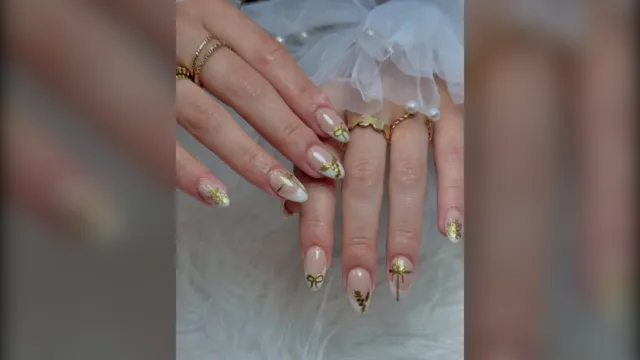 White chrome French tip almond nails with small gold bows