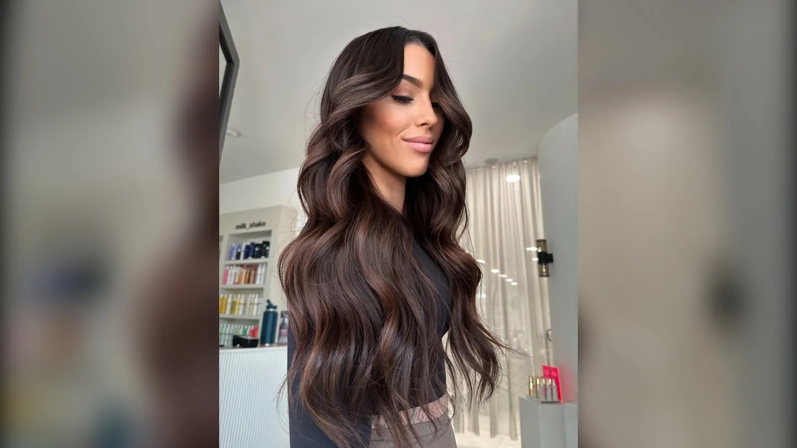 Woman with long glossy chocolate brown waves, winter hair color for brunettes