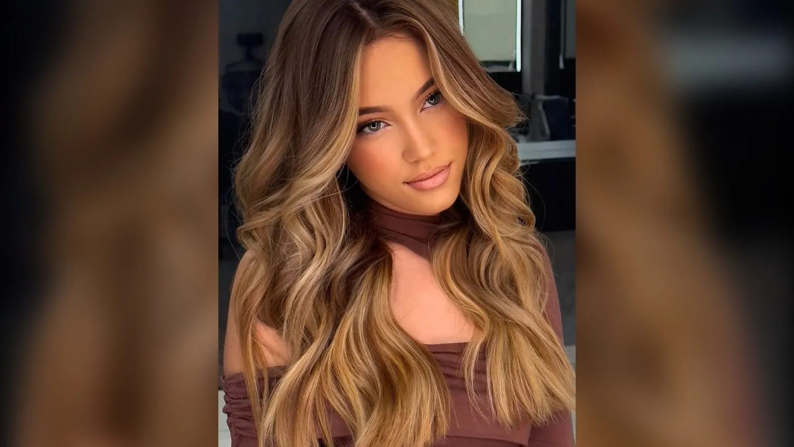 Woman with long wavy brown hair and honey caramel balayage, winter hair color idea