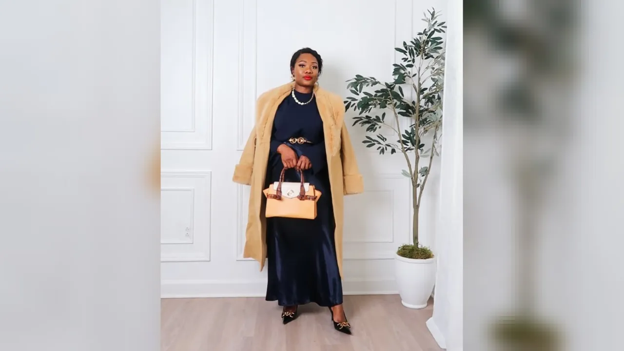Woman in a navy slip maxi skirt, knit sweater and camel faux fur coat